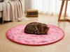Round heart-print cat play pouch on a wood floor